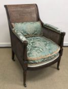 A circa 1900 mahogany framed and double caned Bergere armchair in the Regency style with guilloche,