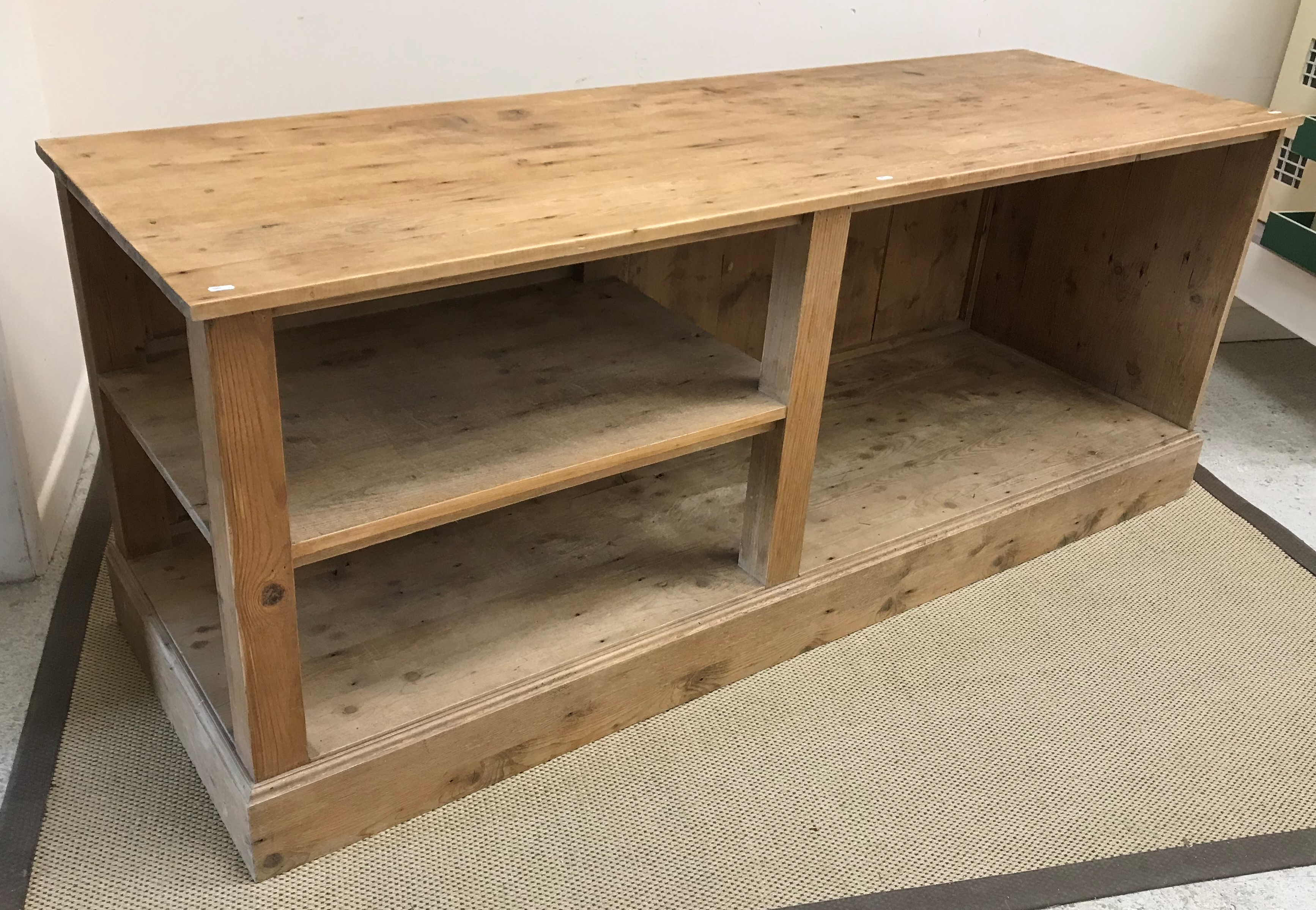 A 20th Century pine kitchen or shop unit, the plain top above an open recess and shelf,