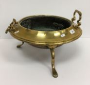 A brass and copper twin-handled dish / planter, raised on three legs to claw feet,