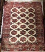 A Turkish prayer rug, the central shaped panel set with repeating red motifs on a cream ground,