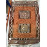 A tribal Kelim rug, the central panel set with two rectangular medallions on an orange ground,