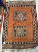 A tribal Kelim rug, the central panel set with two rectangular medallions on an orange ground,