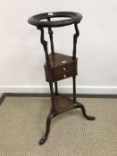 A Georgian mahogany circular washstand, the dished top on scrollwork decorated turned supports,