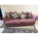 A modern burgundy upholstered sofa with green and burgundy check cushions,