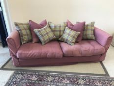 A modern burgundy upholstered sofa with green and burgundy check cushions,