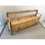 A European stained and waxed pine box seat hall settle, with spindle back over a plain seat,