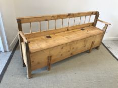 A European stained and waxed pine box seat hall settle, with spindle back over a plain seat,