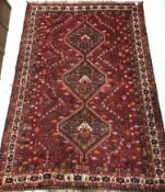 A Persian carpet, the central panel set with three repeating medallions on a red ground,