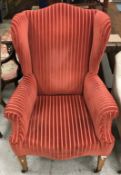 A circa 1900 terracotta striped upholstered wing back scroll arm chair on square tapered legs to