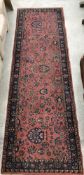 A Persian runner, the central panel set with all-over scrolling foliate decoration on a pink ground,