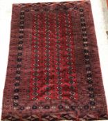 A Bokhara rug, the central panel set with repeating elephant foot medallions on a dark red ground,