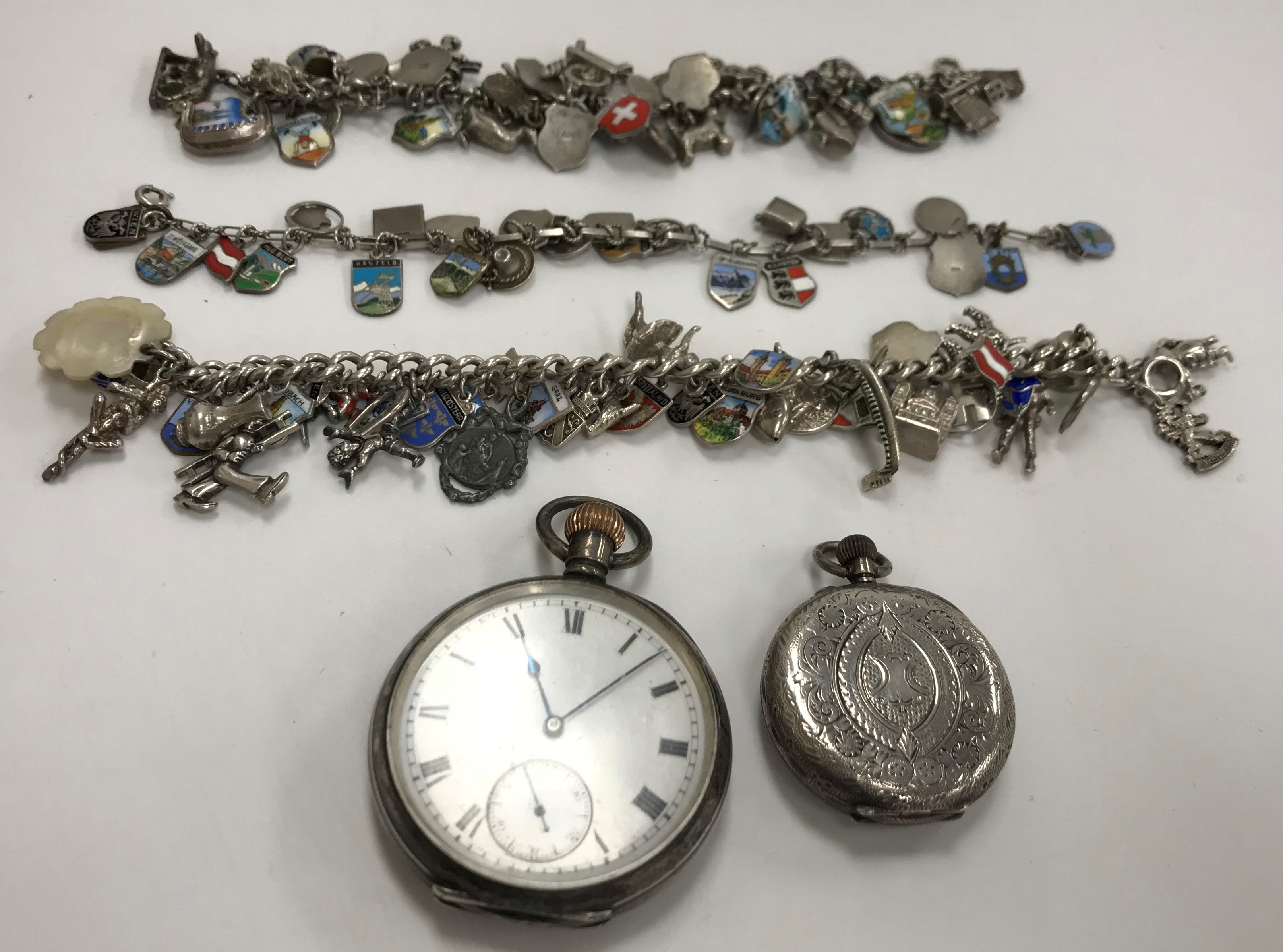 Three various mid 20th Century silver and white metal charm bracelets,