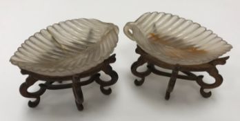 A pair of Chinese carved agate leaf bowls or dishes, with scroll work decorated wooden stands, 8.
