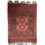 A Bokhara rug, the central panel set with two stylised elephant foot medallions on a red ground,