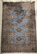 A Bokhara rug, the central panel set with four repeating medallions on a pale blue ground,