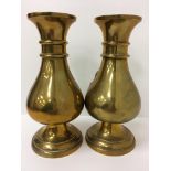 A pair of Chinese brass baluster shaped vases with ringed necks and flared rims raised on a