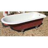 A cast iron enamel roll top bath raised on claw and ball feet,