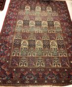 A Persian carpet, the burgundy ground set with repeating tiled decoration,