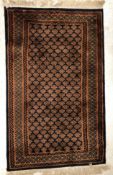 A Bokhara rug, the central panel set with repeating stylised motifs on a dark blue ground,