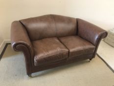 A Laura Ashley "Gloucester" brown leather upholstered scroll arm two seat sofa on turned front legs