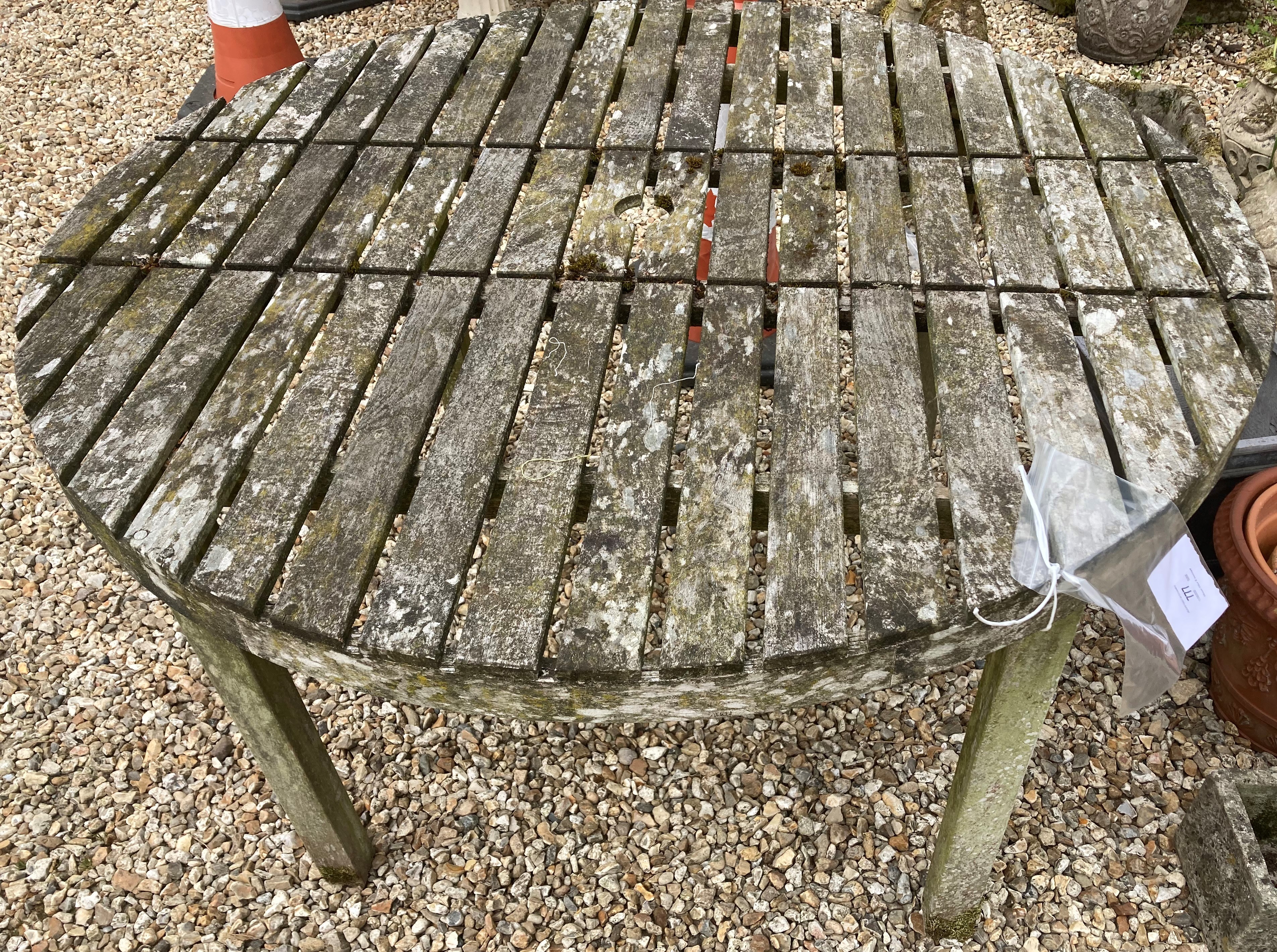 A weathered teak circular garden table,