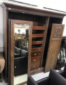 A late Victorian walnut wardrobe compactum with foliate carved doors flanking a central mirrored
