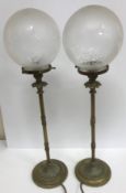 A pair of brass table lamps of reeded column form raised on circular bases with glass globe shades