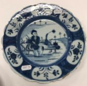 An 18th Century Dutch Delft chinoiserie decorated plate with figure seated upon a table, with flask,