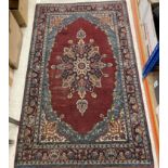 A Persian rug, the central panel set with stylised flower head medallion on a plum ground,