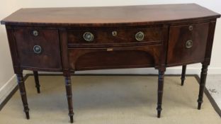 An early 19th Century mahogany bow fronted sideboard with central drawers flanked by cellerette