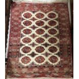 A Turkish prayer rug, the central shaped panel set with repeating red motifs on a cream ground,