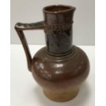 A late 19th Century Martin Brothers pottery jug with brown glaze and acanthus style decoration to