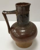 A late 19th Century Martin Brothers pottery jug with brown glaze and acanthus style decoration to