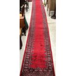 A Bokhara runner, the central plain red panel within a stepped red,