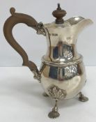 A silver lidded cream jug of baluster form raised on three shell feet (some denting) (by Reid &