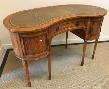 A 20th Century satinwood kidney-shaped writing table in the Sheraton manner,