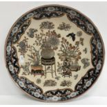A Chinese plate, set with vases of flowers on an ivory ground within a black border, 31.