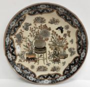 A Chinese plate, set with vases of flowers on an ivory ground within a black border, 31.