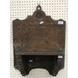 An oak wall shelf with carved intertwined circular decoration and stylised flower heads, dated 1672,