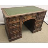 A late Victorian oak kneehole desk, the tooled and gilded leather insert top over a central drawer,