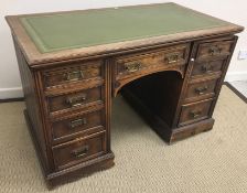 A late Victorian oak kneehole desk, the tooled and gilded leather insert top over a central drawer,
