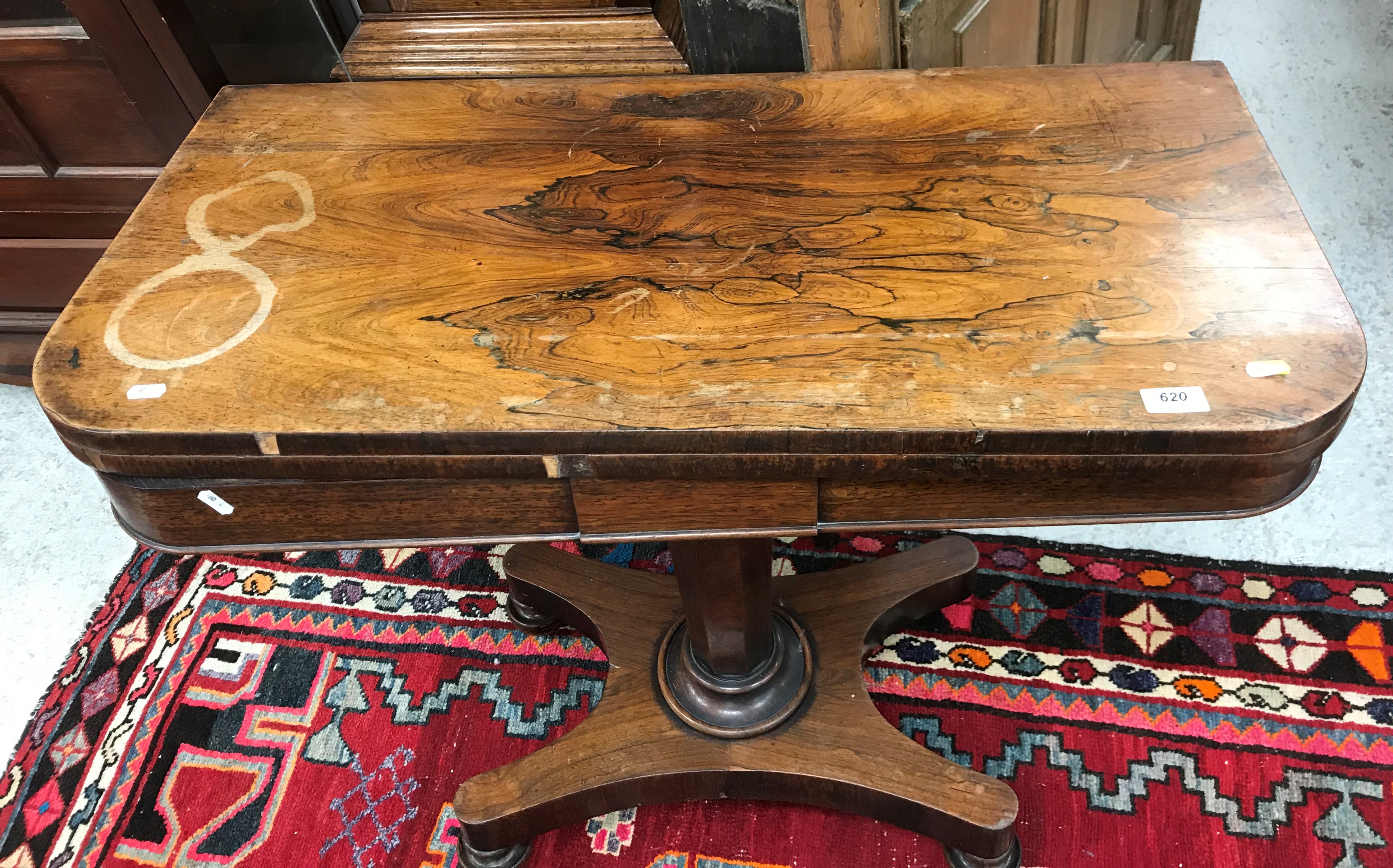 A Victorian rosewood fold over card table on tapering octagonal base to platform quadruped supports