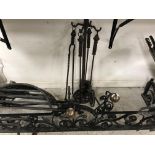 A wrought iron scrollwork decorated fire fender with central flower head medallion and ball end