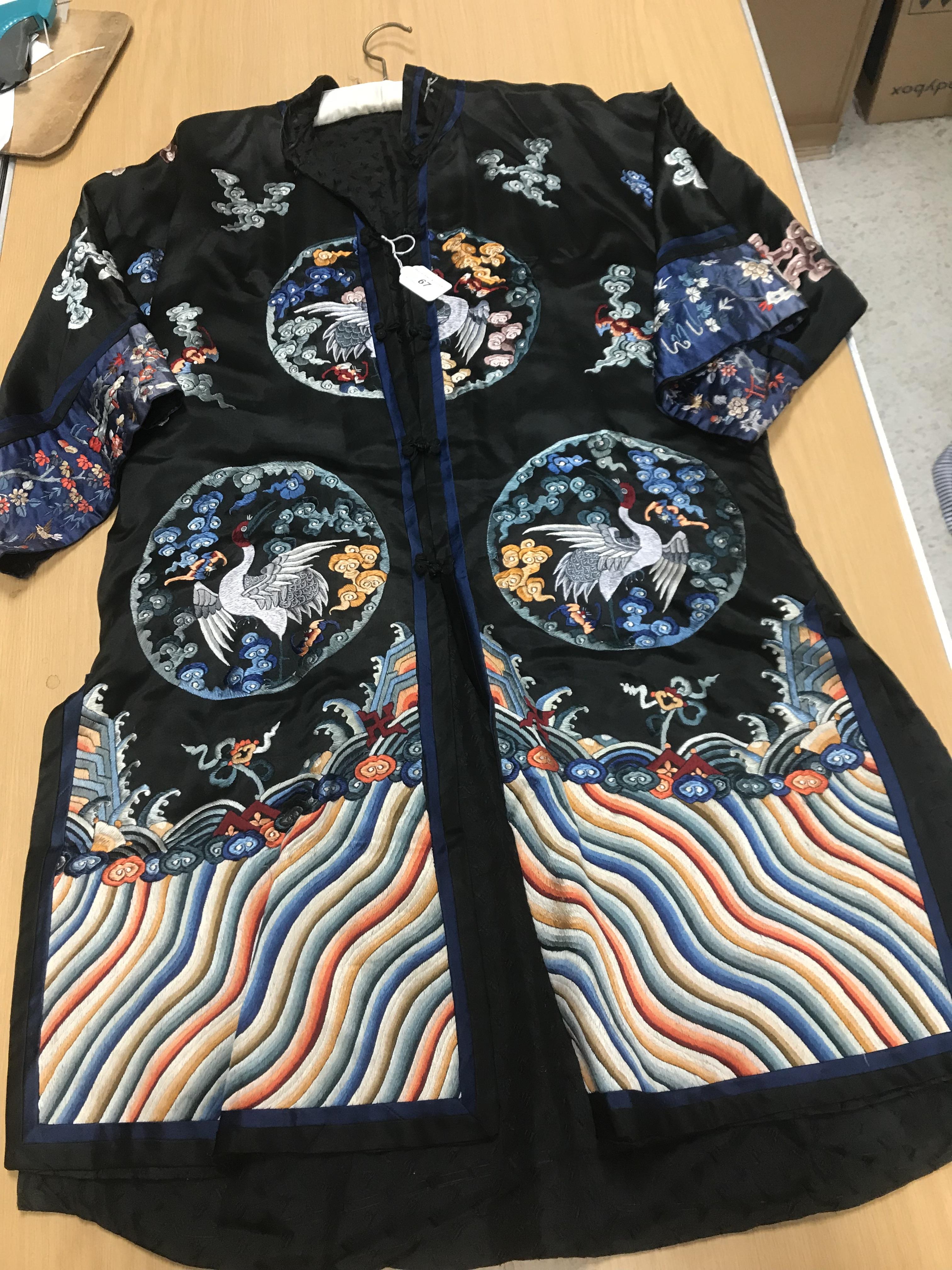 A Chinese silk jacket with crane and wave decoration on a black ground