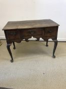 An 18th Century oak lowboy, the two plank top over three drawers and fretwork carved frieze,