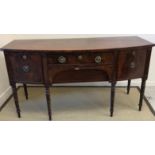 An early 19th Century mahogany bow fronted sideboard with central drawers flanked by cellerette