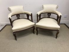 A pair of Edwardian mahogany framed and upholstered low tub chairs on cabriole legs to castors