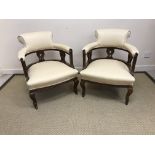 A pair of Edwardian mahogany framed and upholstered low tub chairs on cabriole legs to castors