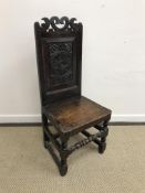 A 17th Century style oak panel seated hall chair with crown carved top rail over a Tudor rose and