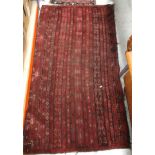 A tribal rug, the central panel set with striped design on a red and black ground,